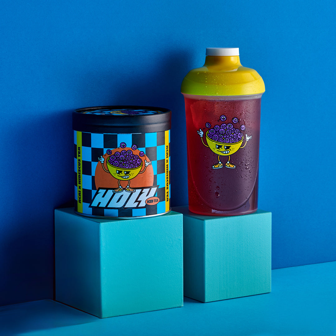 Bunte Pappdose und durchsichtiger Shaker mit lustigem Design auf blauen Blöcken vor blauem Hintergrund.
