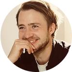 Ein lächelnder Mann mit Bart, der in die Ferne schaut.