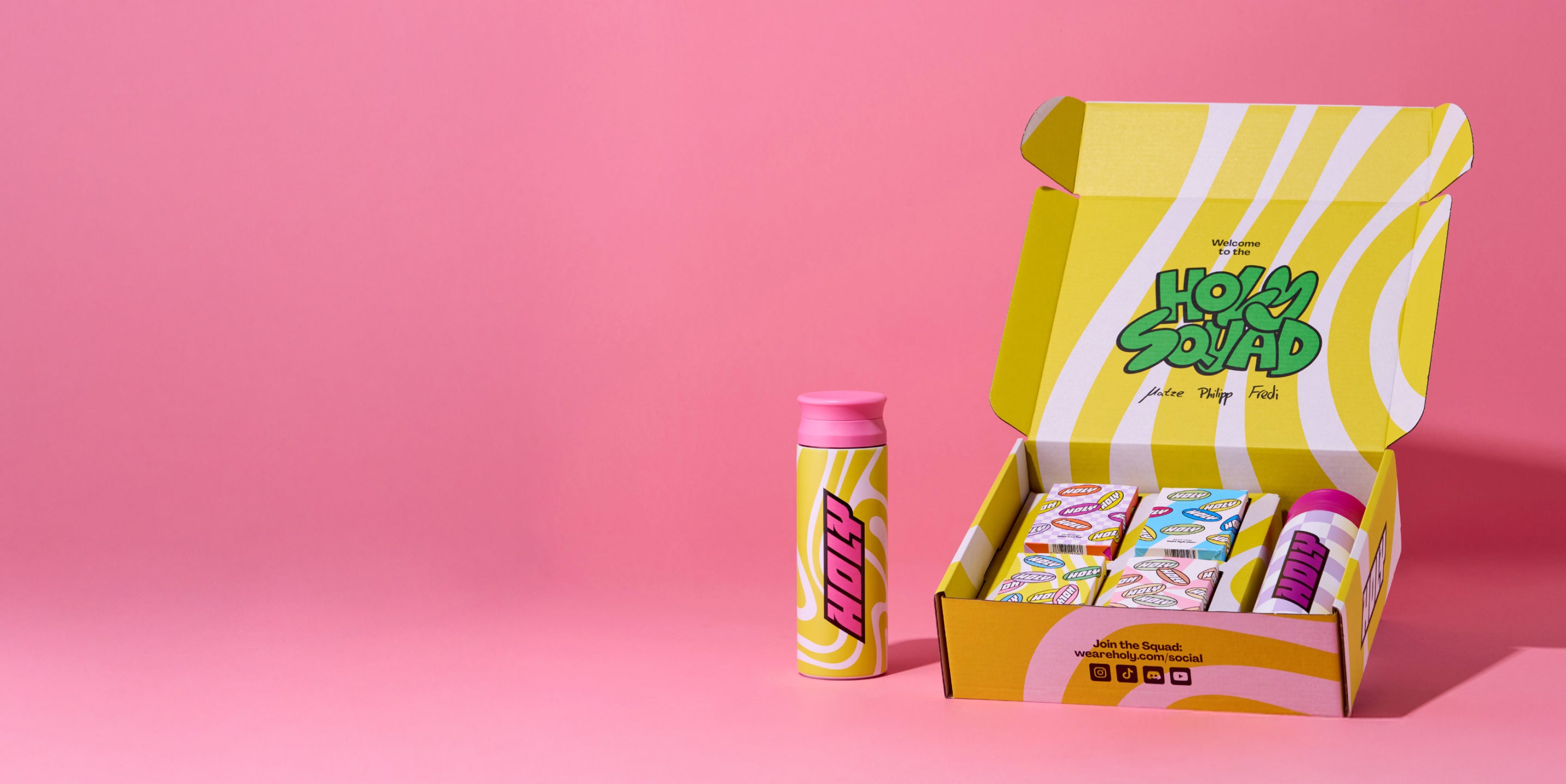 Gelbe Pappbox mit Sachets und ein gelber Shaker auf rosa Hintergrund.
