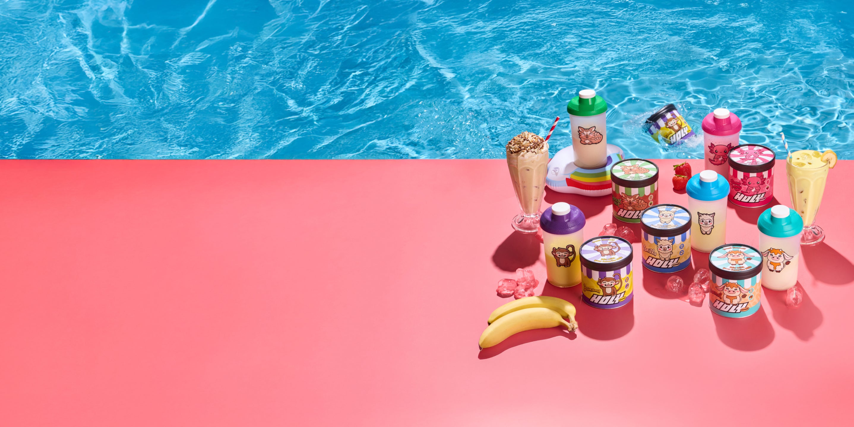 Verschiedene Pappdosen, Shaker und Getränke auf einem roten Tisch am Pool, umgeben von Eiswürfeln und Früchten.