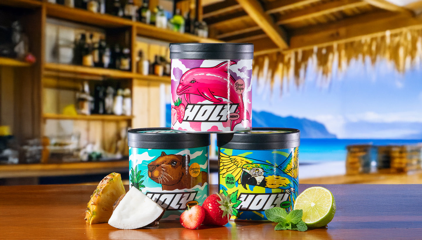 Drei bunte Pappdosen mit Tiermotiven auf einem Tisch, umgeben von Ananas, Kokos, Erdbeeren, Minze und Limette.